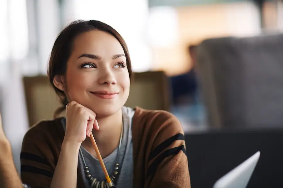 Smiling woman resting her chin on her hand, looking hopeful while reflecting during her recovery journey.