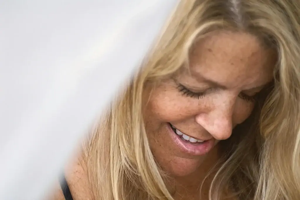 Smiling woman with blond hair looking down, conveying hope and peace in recovery.